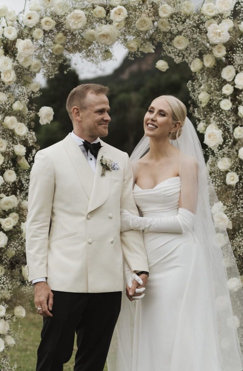 Couple beneath a white rose arch